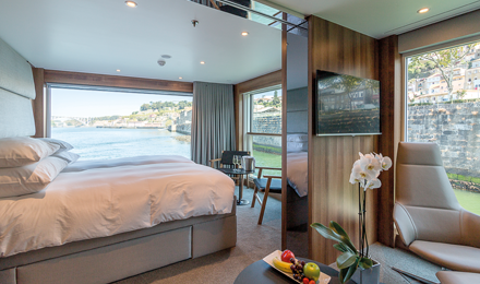 Emerald Waterways river cruise ship accommodations with bed, large windows and sitting area