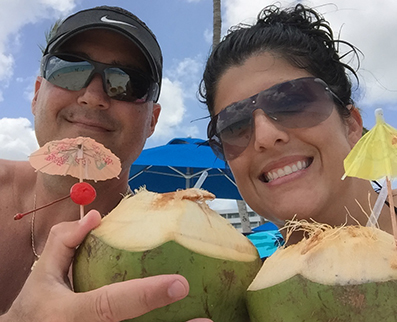 Testimonials: cute couple celebrating with a tropical drink inside of a coconut