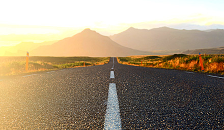 A roadway with a sunset and mountains
