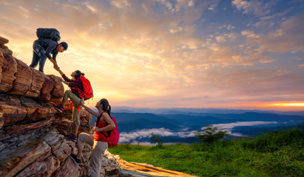 Three rock climbers climbing a rock at sunset