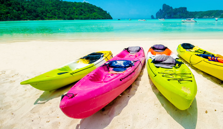 Brightly colored kayaks sitting side by side on a beach in the Caribbean