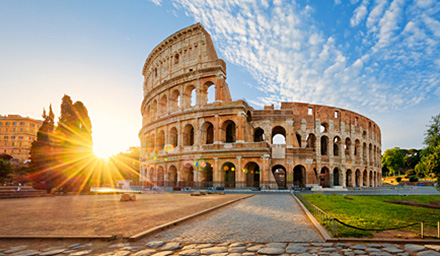The Colosseum against a blue sky with a sun burst on the left