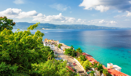 Palm trees, tropical buildings and blue shoreline in Jamaica