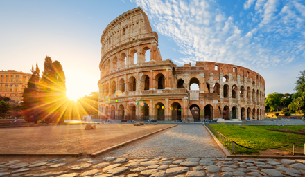 The Colosseum in Rome with a large sun burst in the background