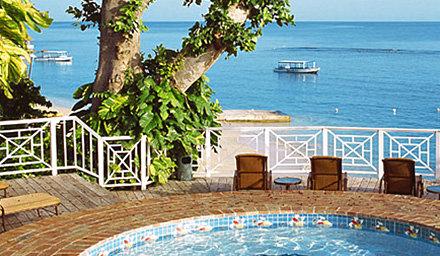 A jacuzzi with lounge chairs with the ocean water in the background at a Sandals Resort