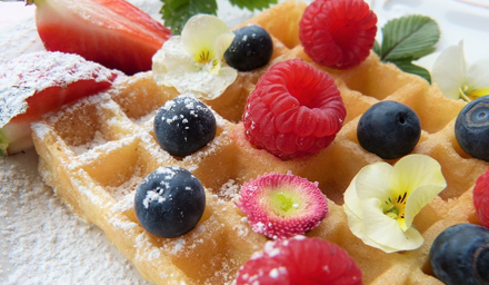 A plate of waffles with fresh fruit and flowers