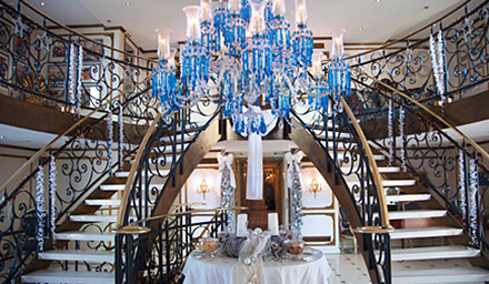 Two staircases with a blue chandelier hanging from the ceilin