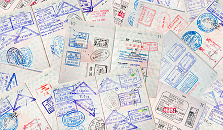 A layered collage of multiple passports with a lot of colorful passport stamps on the pages