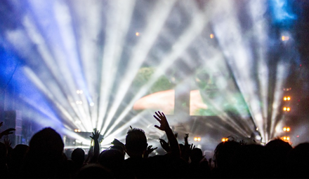 A crowd of people at a concert with light and smoke effects